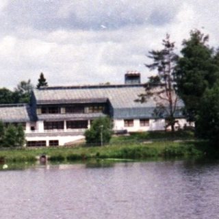 Serene lake with buildings and forested shoreline.