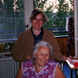 Four people posing indoors near kitchen window.