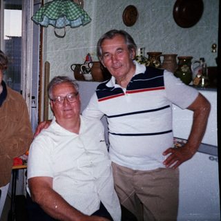 Four elderly people posing happily indoors together.