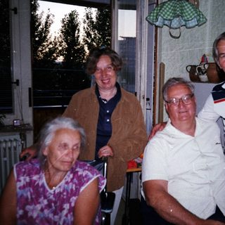 Four elderly people posing happily indoors together.