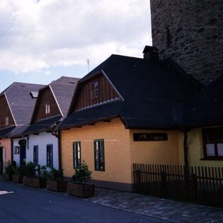 Quaint village street with colorful houses and stone tower.