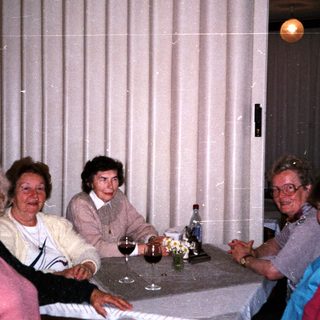 Family gathering indoors around a table with drinks.