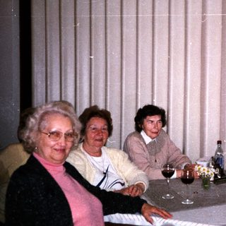 Family gathering indoors around a table with drinks.