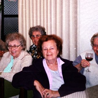 Group of elderly people enjoying drinks indoors.