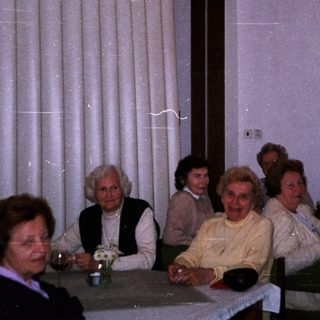 Group of elderly people gathered indoors for a social event.