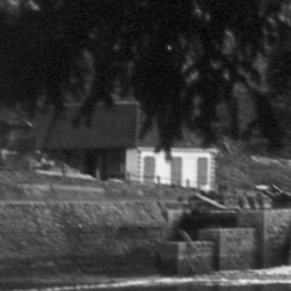 Rural waterfall-fed irrigation channel with small structures.