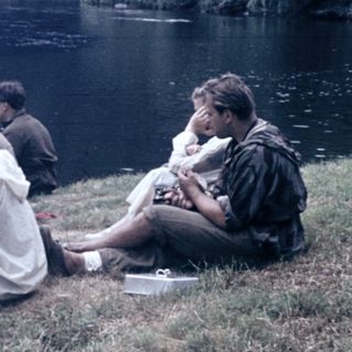 People relaxing by a lake with a canoe.