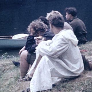 People relaxing by a lake with a canoe.