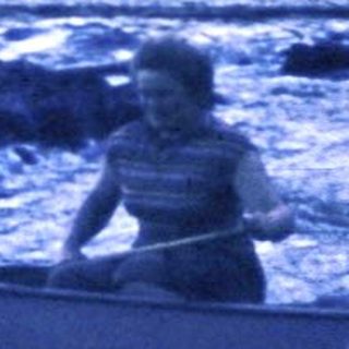 Two people paddling a canoe on turbulent river at night.