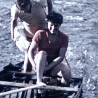 Two people paddling a wooden canoe on water.