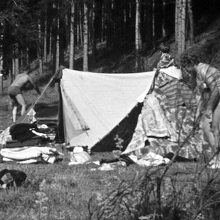People camping outdoors with tents and gear.