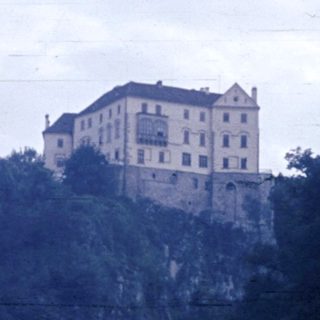 Castle perched on rocky cliff by lake.