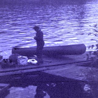 Person standing on floating wooden dock by water.