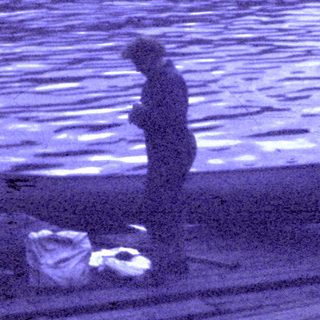 Person standing on floating wooden dock by water.