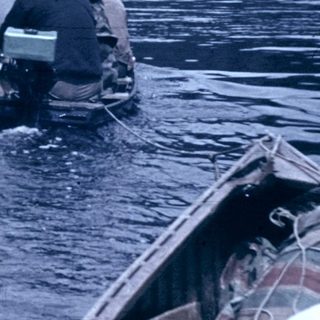 Two divers entering water near rocky coastline.