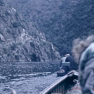 Boat on deep blue water near steep cliffs.