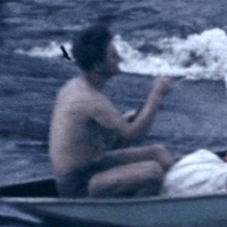 Two people rowing a small boat on turbulent water.