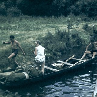 People loading supplies into a canoe near water.