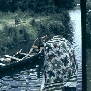 People loading supplies into a canoe near water.