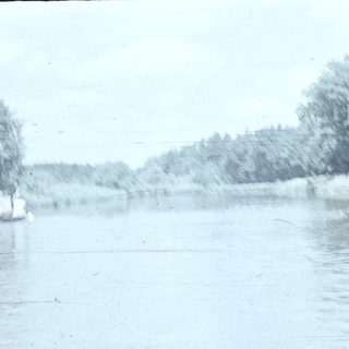 Two people rowing a small boat on a rainy river.