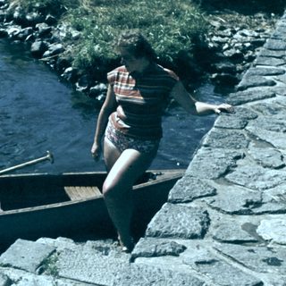 Person launching canoe into flowing river.