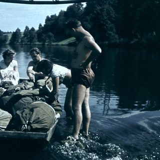 People loading a boat with luggage near a lake.