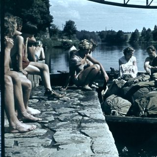 People loading a boat with luggage near a lake.