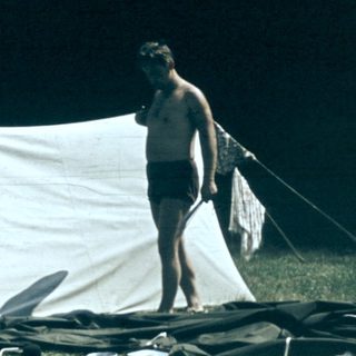 People camping outdoors with tent and gear.