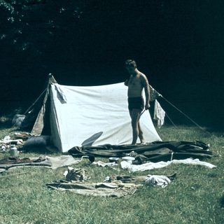 People camping outdoors with tent and gear.