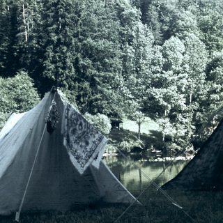 Campsite with tents near a lake in forested area.