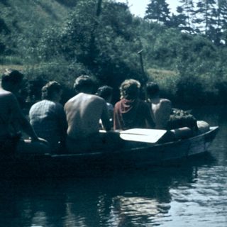 People rowing a wooden boat on calm water.