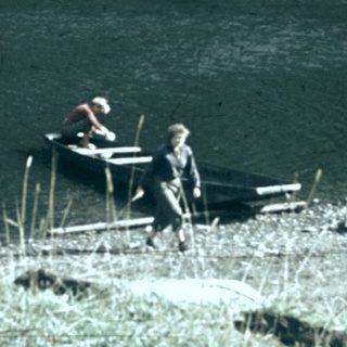 People relaxing by a lake with chairs.