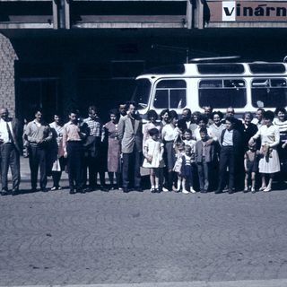 Group posing with vintage bus outside building.