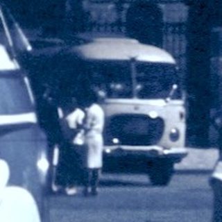 Vintage street scene with couple talking near bus.