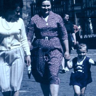 Family walking together in vintage street attire.