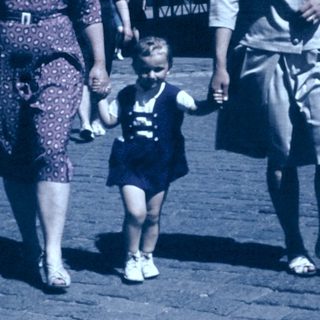 Family walking together in vintage street attire.