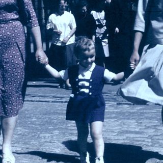 Three women and a child walking together outdoors in vintage clothing.