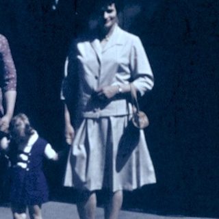 Group of people walking outdoors in vintage clothing.