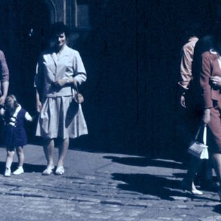 Group of people walking outdoors in vintage clothing.