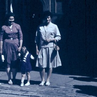 Group of people walking outdoors in vintage clothing.