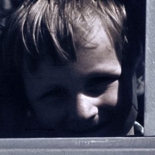 Two children looking out of a moving vehicle window.