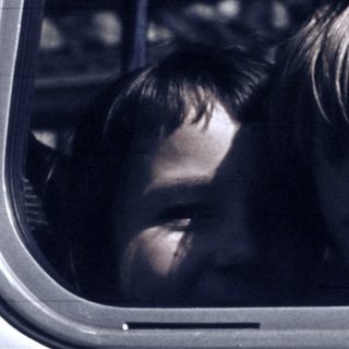Two children looking out of a moving vehicle window.