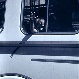 Child waving from a moving bus window.