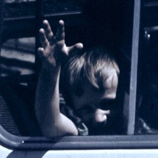 Child waving from a moving bus window.