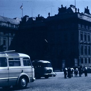 Historic street scene with vintage vehicles and grand building.