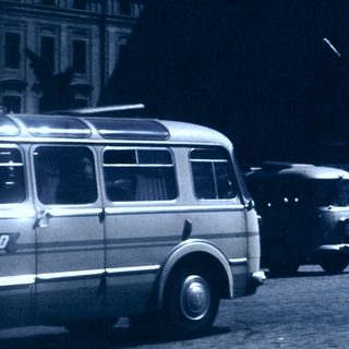 Historic street scene with vintage vehicles and grand building.