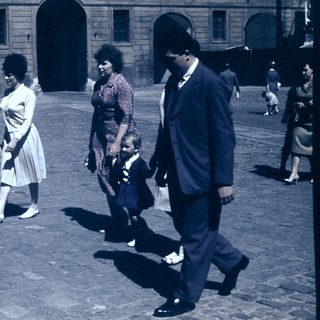Family walking in courtyard near historic building.