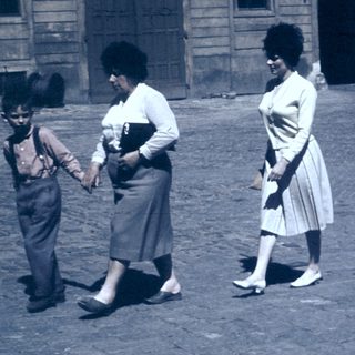 Family walking in courtyard near historic building.