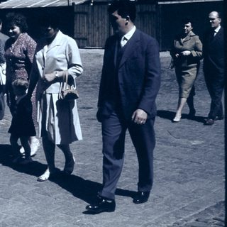 People walking in a cobblestone street, mid-20th century.