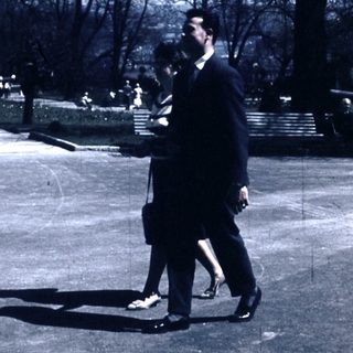 Couple walking in park on sunny day.